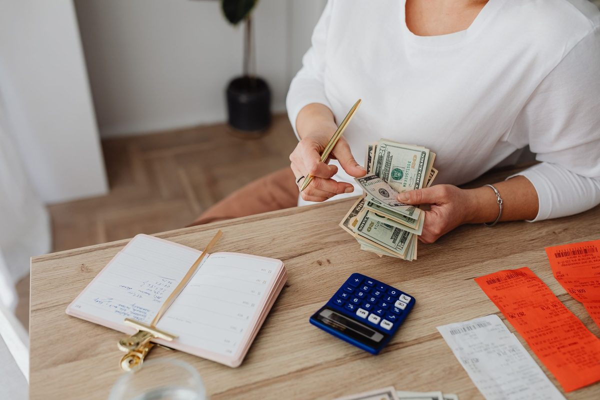 Personne comptant son budget ménager avec calculatrice et billets