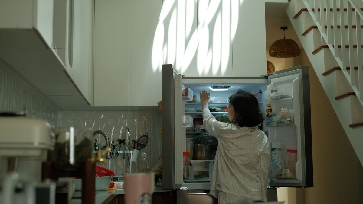 Personne rangeant des aliments dans un réfrigérateur ouvert