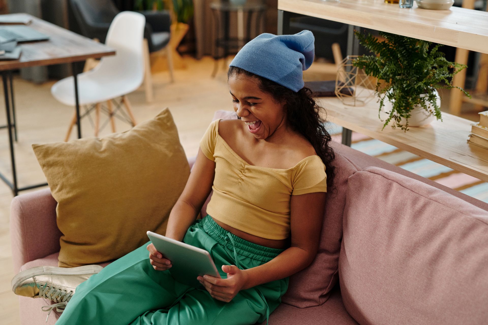 adolescent souriant utilisant une tablette, assis sur un canapé
